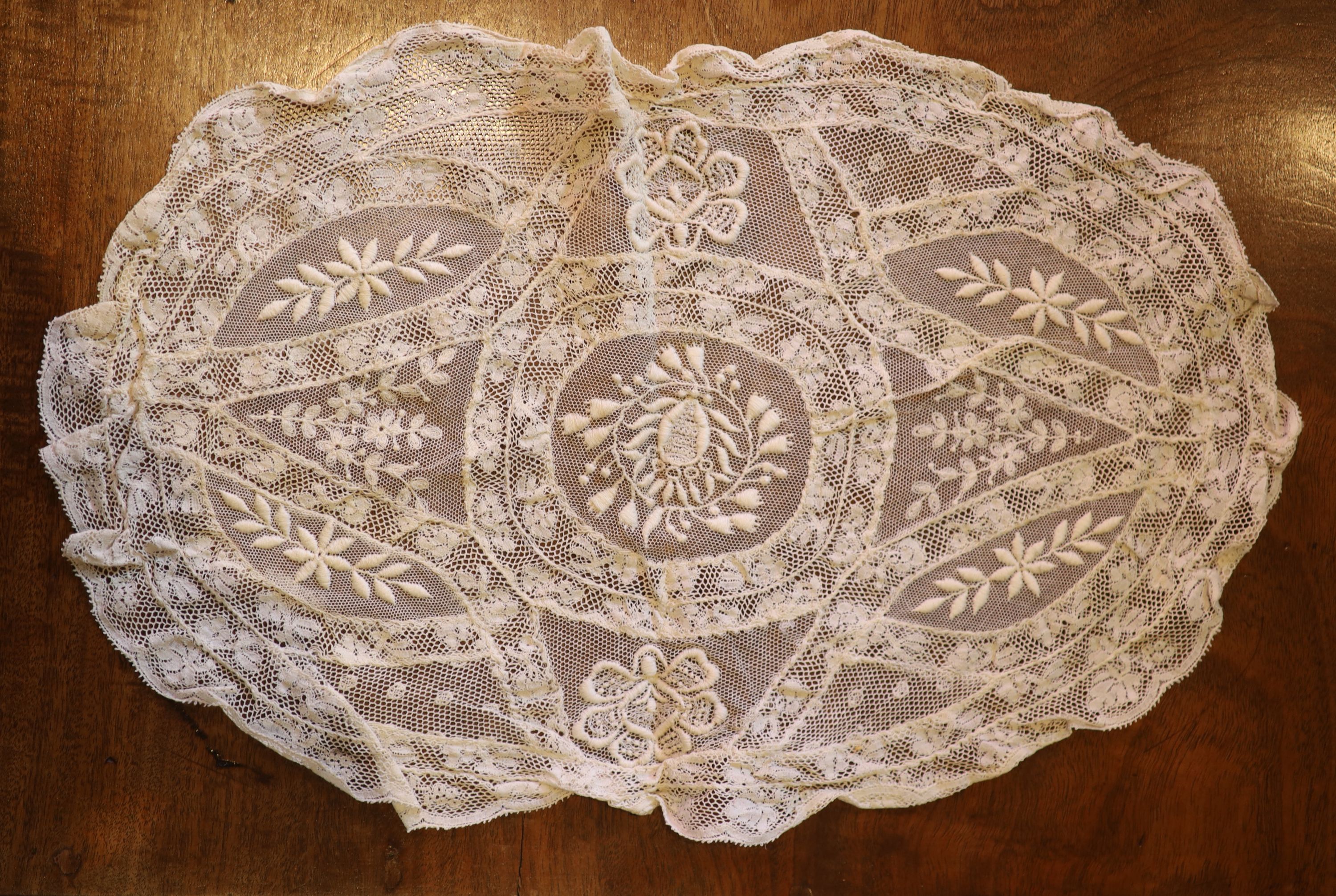 A square Normandy lace table cloth and approximately nineteen circular place mats and a centrepiece,